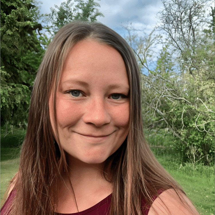 Smiling woman outdoors with trees background.
