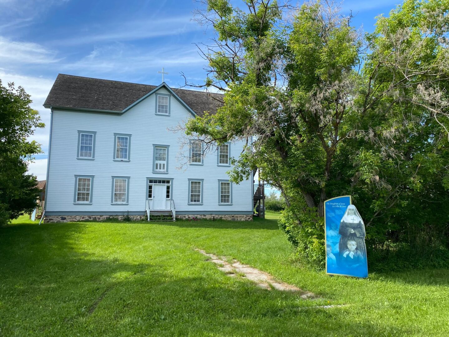 Historic white house with lush green surroundings.