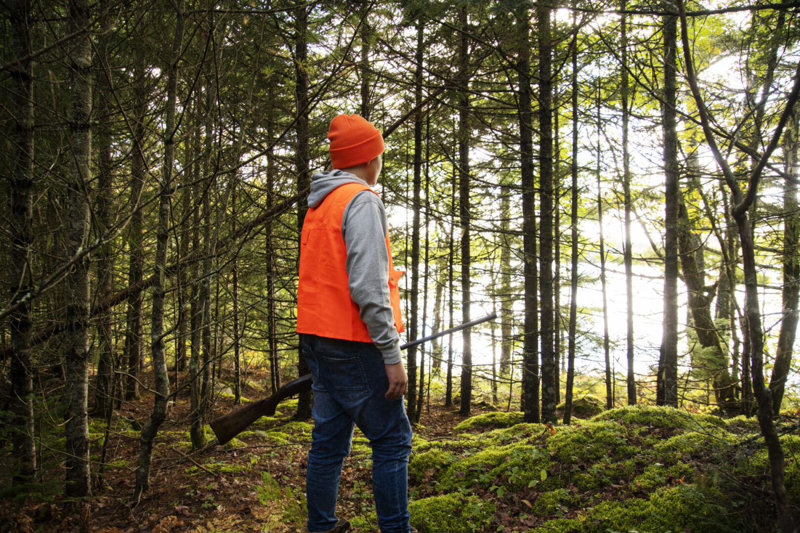 Hunter in bright gear standing in forest.
