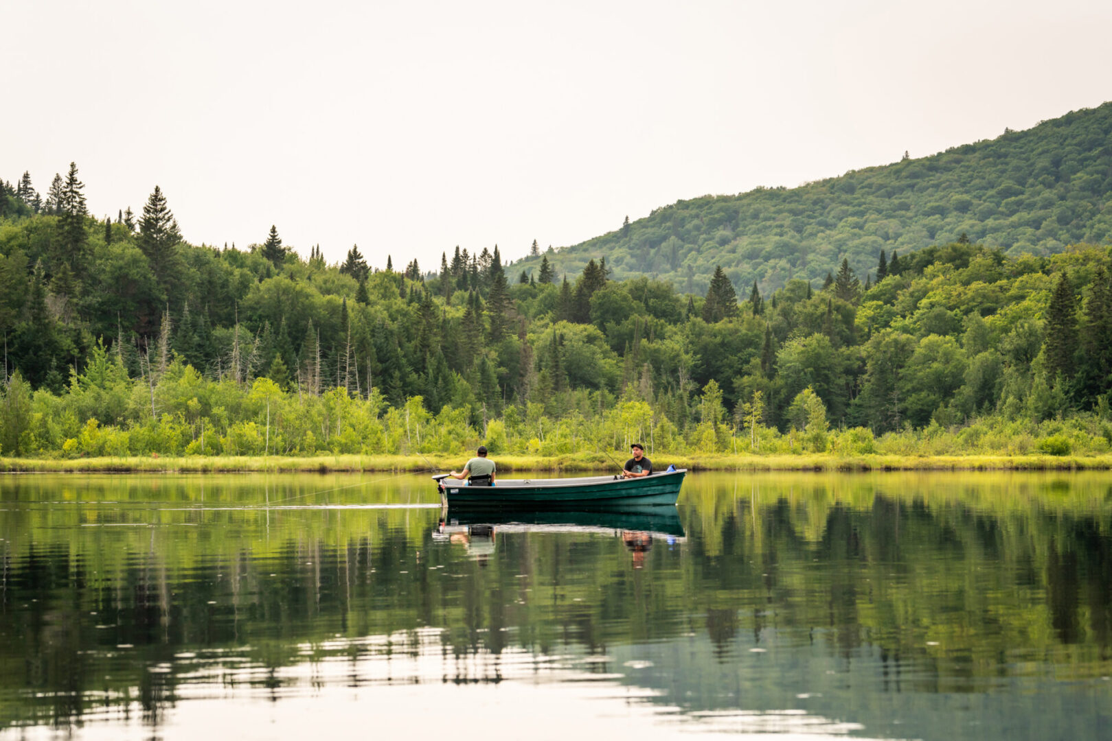 Boat on calm lake surrounded by forest.