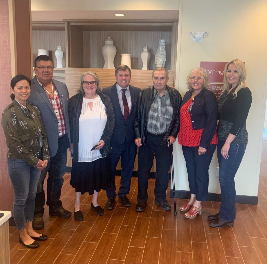 Group of people standing indoors, smiling.