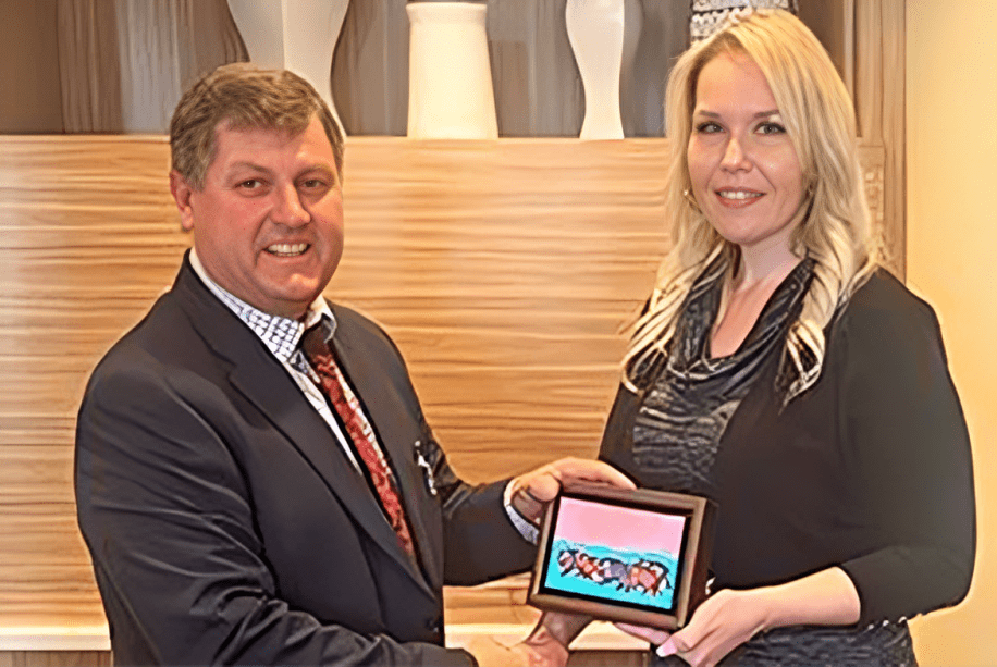 Two people holding a framed picture together.