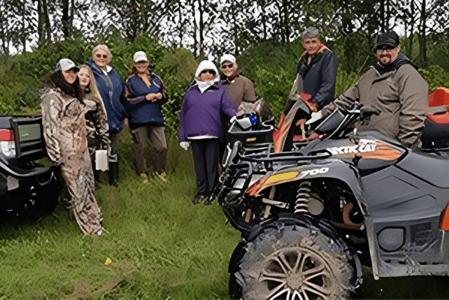 Group with ATVs in grassy area.